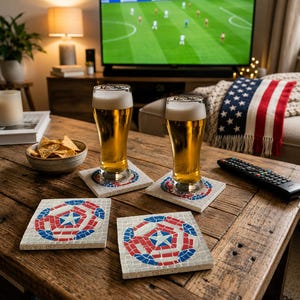 May include: Four square coasters featuring a mosaic design of a central white star surrounded by red, white, and blue tiles. Two coasters are placed under tall glasses filled with golden beer, while two others sit empty on a rustic wooden table.