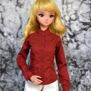 May include: A doll with long blonde hair wearing a red collared shirt with buttons and white shorts.