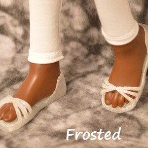 May include: White sandals with a frosted finish. The sandals have a criss-cross strap design and are made of a clear plastic material.