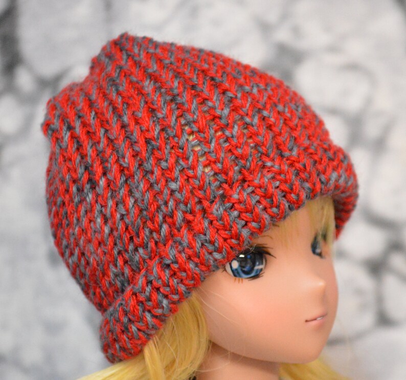 May include: A red and gray knitted beanie hat with a chevron pattern.