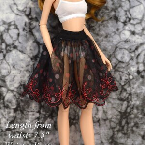 May include: A black tulle skirt with red embroidery and white polka dots. The skirt is 7.5 inches long and the waist adjusts from 6.5 to 7 inches.