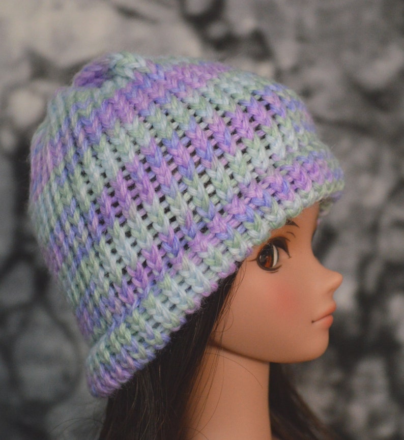 May include: A knitted hat in shades of purple, blue, and green. The hat has a ribbed texture and a slouchy fit.