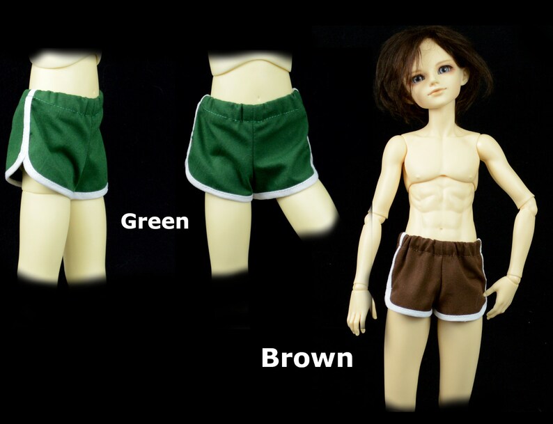 May include: Two pairs of doll-sized athletic shorts, one green and one brown, with white trim. The shorts have a retro style.