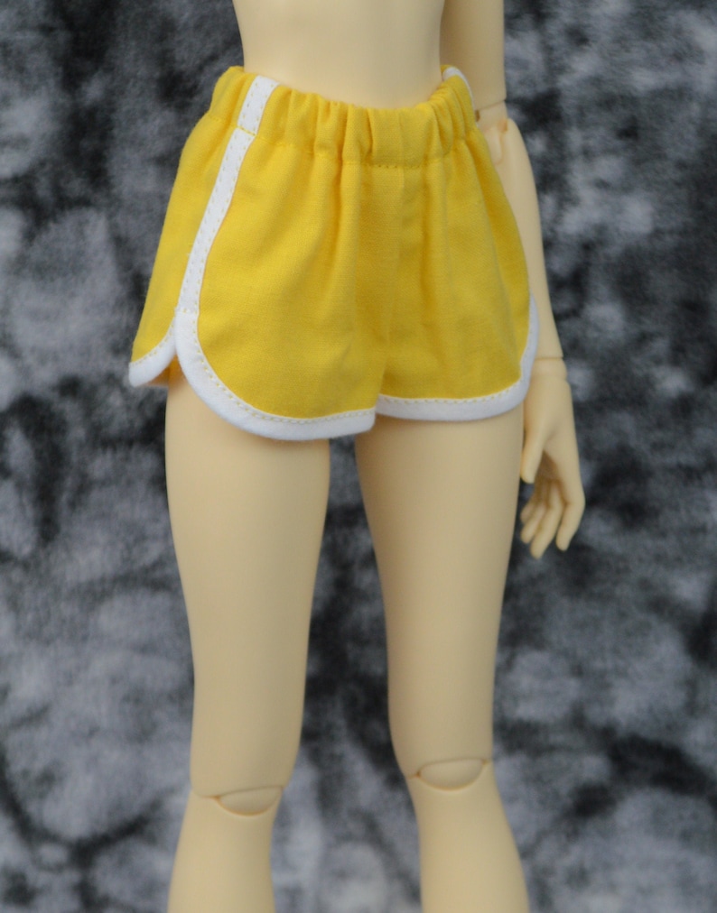 May include: Yellow athletic shorts with white piping. The shorts have a drawstring waist and are made of a soft, comfortable fabric.