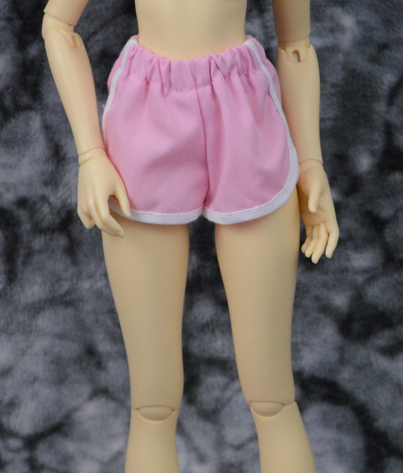 May include: Pink athletic shorts with white trim. The shorts have a drawstring waistband and are made of a soft, comfortable fabric.