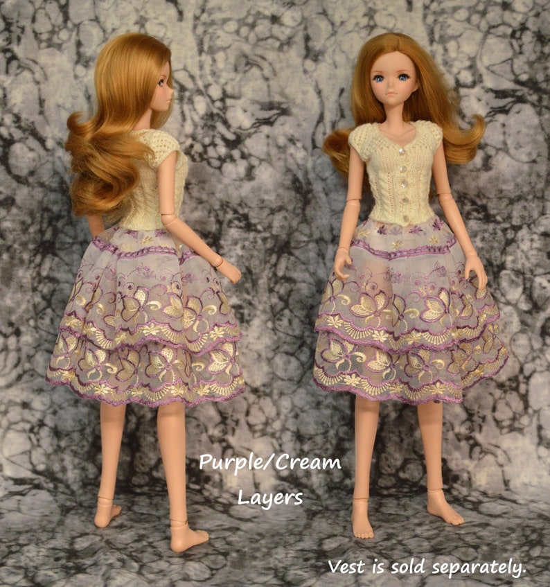 The embroidered design on this lace appears as purple and cream butterflies, trimmed with embroidered flowers. Scalloped lace is layered for added fullness, making this skirt OOAK. Waistband is lined in white and snaps closed in back.