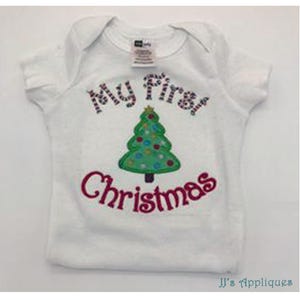 May include: A white short-sleeved baby bodysuit featuring an embroidered green Christmas tree with colorful circular ornaments. The text "My First" is stitched in a red and white striped pattern above the tree, and "Christmas" in red below.
