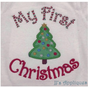 May include: A white fabric surface featuring an embroidered green Christmas tree with colorful circular ornaments and a gold star topper. The text My is embroidered in red and green stripes above, and the word Christmas in red below.
