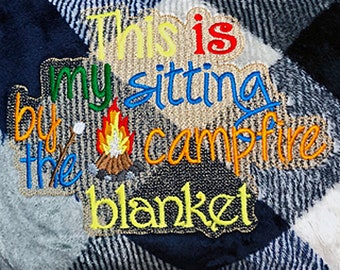 May include: A blue and white plaid blanket with the embroidered text "This is my sitting by the campfire blanket".