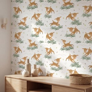 May include: A wall covered in wallpaper featuring a repeating pattern of running deer in shades of brown and tan. The deer are interspersed with green grass and small white leaf-like shapes on a white background. A wooden cabinet with decorative bottles and a basket is in the foreground.