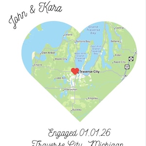 May include: A heart-shaped map of Traverse City, Michigan, with a red heart marking the location. The names "John & Kara" are above the map, and "Engaged 01.01.26 Traverse City, Michigan" is below.