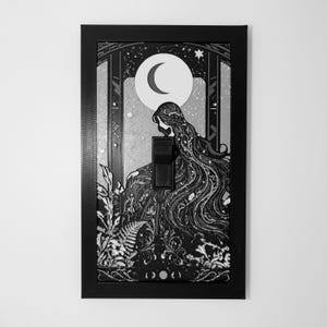 May include: A rectangular black light switch cover plate featuring a detailed monochrome illustration of a long-haired figure sitting beneath a crescent moon, surrounded by stylized foliage, stars, and a central black toggle switch.