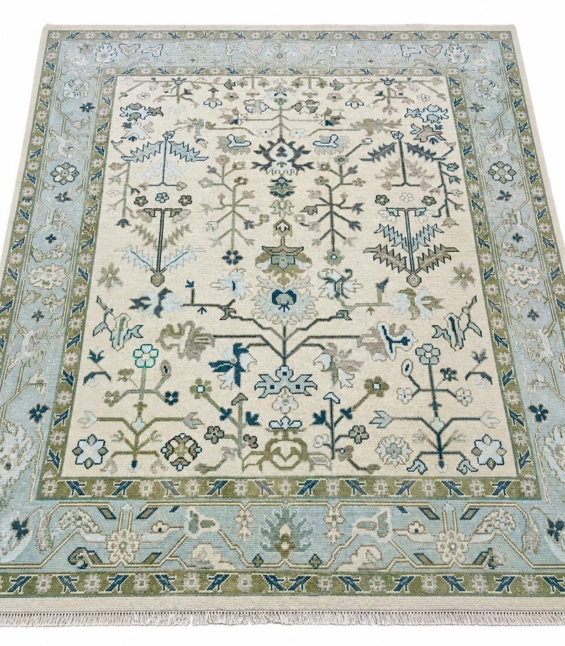 A luxurious hand knotted rug featuring a zero-pile cream base with powder blue borders and beautiful botanical motifs.