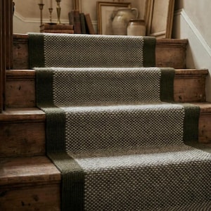 May include: A stair runner featuring a textured, woven gray and beige center panel with solid dark olive green borders on each side. The runner is installed over wooden stairs, covering the treads and risers in a continuous, fitted pattern.