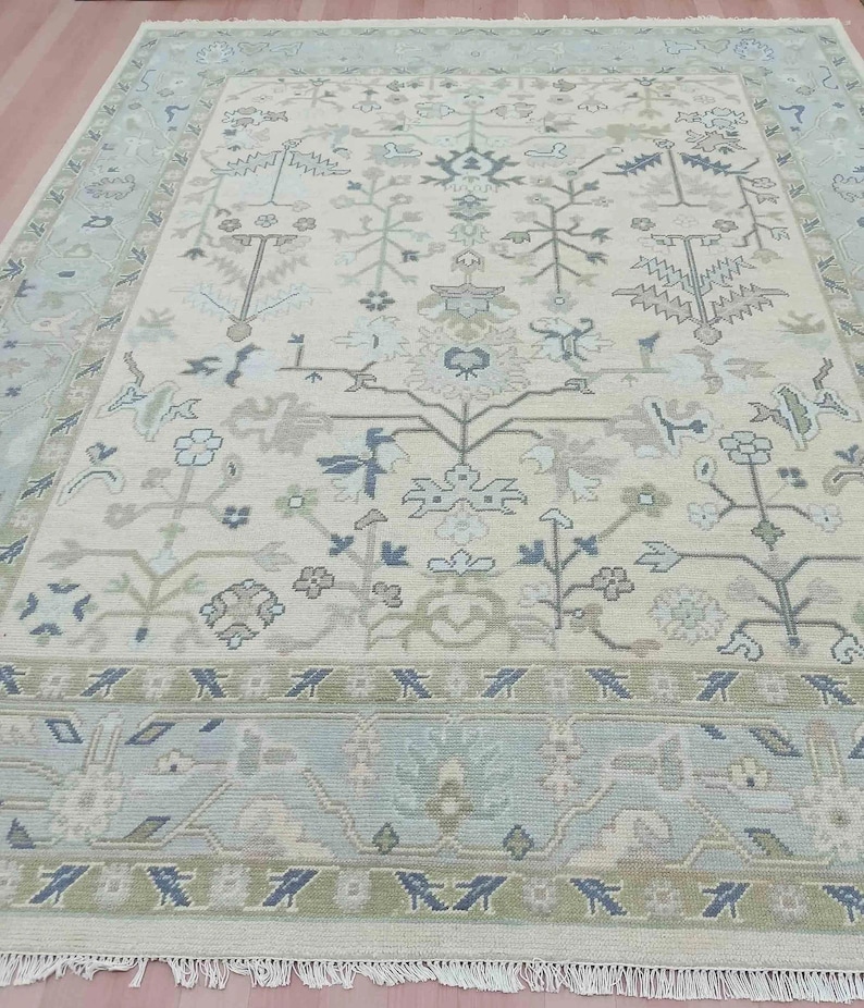 Close-up of the wool rugs surface, showcasing the sleek hand-knotted zero-pile texture and olive green chevron border.