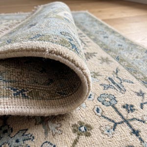 A bespoke 8x10 rug styled in a bright, airy living space showcasing its crisp cream and blue palette.