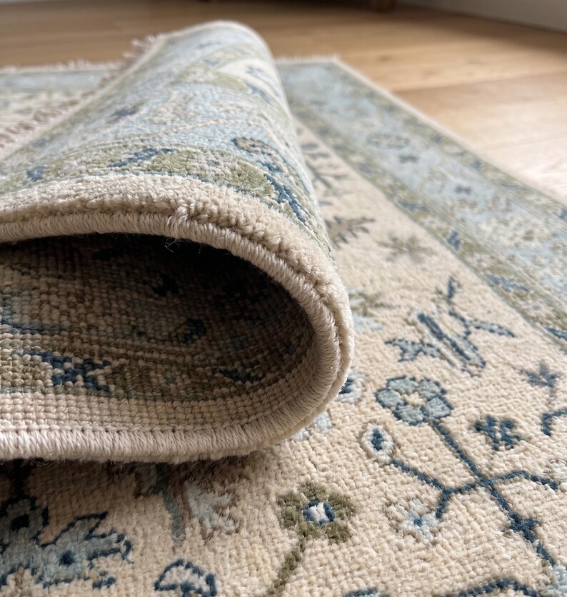 A bespoke 8x10 rug styled in a bright, airy living space showcasing its crisp cream and blue palette.