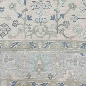 Detailed view of the navy blue floral accents and warm taupe vine patterns on this stunning ivory rug.
