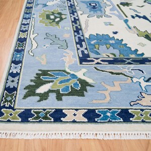 Close-up of large-scale tribal floral patterns in various shades of blue on a wool rug white background.