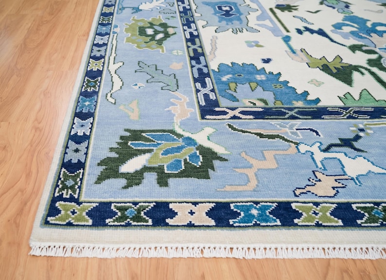 Close-up of large-scale tribal floral patterns in various shades of blue on a wool rug white background.