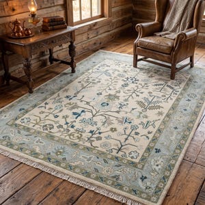 Natural light highlighting the bright ivory base, sage green leaves, and soft peach accents of this blue rug large.