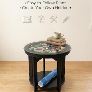 Op de afbeelding: Een ronde zwarte houten tafel met een glazen blad met daaronder een verzameling kleine steentjes en snuisterijen. De tafel heeft een onderste plank met een blauwe opgerolde bouwtekening. Tekst: DIY BUILD PRINTS | The Adventure Memory Table.
