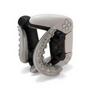 May include: A white and black game controller with silver octopus-tentacle-shaped grips. The controller has a directional pad, buttons, and joysticks. The tentacles curve around the controller.