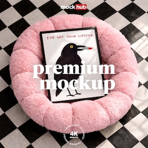 May include: A framed art print featuring a black bird with a red lipstick in its beak, with the text "I'VE GOT YOUR LIPSTICK". The print is displayed on a fluffy pink pet bed. The image has the words "premium mockup" in large white letters.