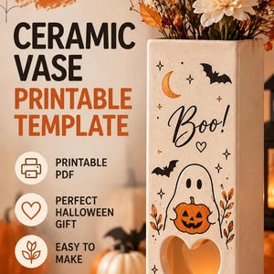 Könnte beinhalten: Eine rechteckige Keramikvase mit einer herzförmigen Aussparung an der Unterseite, verziert mit einem Geist, der einen Kürbis hält, Fledermäusen, Sternen und dem Text "Boo!". Die Vase enthält orangefarbene und weiße Blumen.