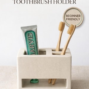 May include: A beige clay toothbrush holder with the text "CLAY TEMPLATE TOOTHBRUSH HOLDER." It holds a tube of toothpaste and two wooden toothbrushes. A circular sticker reads "BEGINNER FRIENDLY."