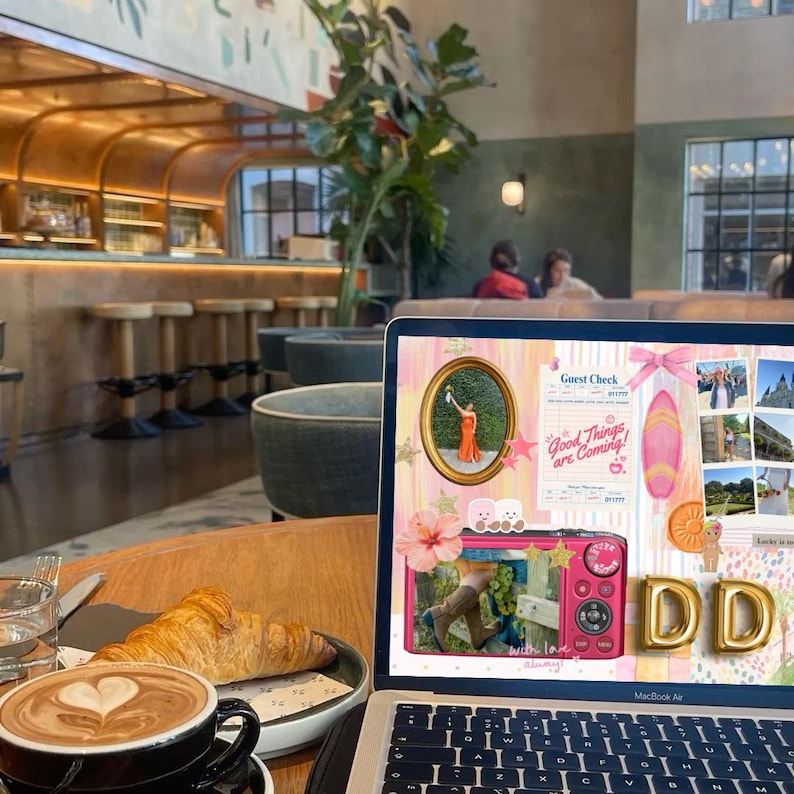May include: A laptop displaying a collage with the text "Good Things are Coming!" sits on a wooden table next to a cup of coffee with latte art and a croissant. The background shows a cafe setting.