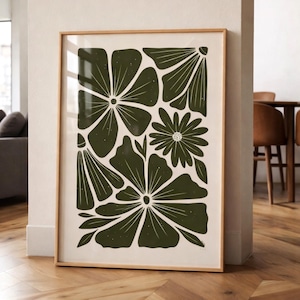 May include: A framed art print featuring a botanical design. The artwork showcases stylized dark green flowers and leaves against a cream background. The print is encased in a light brown wooden frame, leaning against a wall.