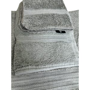 May include: A stack of gray bath towels with a textured surface and striped detailing. The towels are folded and appear soft, with a small black tag visible on one of the towels. The towels are a neutral color.