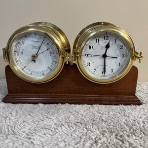 May include: A white ceramic mug with a black handle and the text "But First, Coffee" in a bold, black font. The mug is set against a blurred background, suggesting a cozy setting.