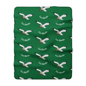 May include: Green blanket featuring a repeating pattern of white eagles with footballs and the text "Go Birds". The blanket is rectangular in shape.