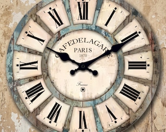 Könnte beinhalten: Eine runde Wanduhr mit einem verwitterten Vintage-Design. Das Zifferblatt zeigt römische Ziffern, schwarze Zeiger und den Text "CAFEDELAGAR PARIS 1870". Die Uhr hat ein hellblaues und weißes Farbschema mit einem verwitterten Aussehen.
