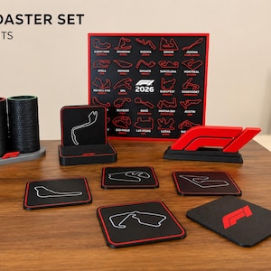 Könnte beinhalten: F1-Strecken-Untersetzer-Set mit 20 ikonischen Rennstrecken. Das Set enthält schwarze Untersetzer mit rotem Rand, die jeweils ein Streckenlayout in Weiß zeigen. Ein schwarzes und rotes F1-Logo ist ebenfalls vorhanden.