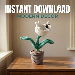 Puede incluir: Una flor de ganchillo en una maceta gris. La flor blanca tiene una abeja negra y amarilla en su interior. El tallo y las hojas verdes están unidos a la flor. El texto "INSTANT DOWNLOAD MODERN DECOR" está en la parte superior de la imagen.