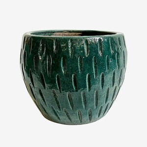 May include: A dark green ceramic planter with a textured surface. The planter has a rounded shape and is covered in vertical, oval-shaped indentations. The interior of the planter is a darker shade of green.