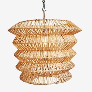 May include: A natural woven rattan pendant light fixture. The light has a layered, geometric design with a series of stacked, horizontal, angled bands. The light hangs from a black chain and has a single lightbulb visible inside.