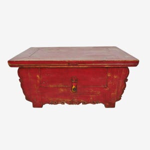 May include: A rectangular, antique red wooden chest with a hinged lid and a single drawer. The chest features ornate carvings on the sides and a metal clasp on the drawer. The paint is distressed, giving it a vintage appearance.