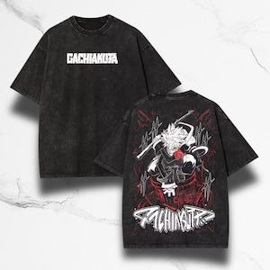 Peut inclure: T-shirt noir délavé à l'acide. Le devant affiche le texte blanc "GACHIAKUZA". Le dos présente un graphisme de style anime rouge et blanc et le texte "GACHIAKUTA" dans une police stylisée. Le t-shirt a un aspect vintage.