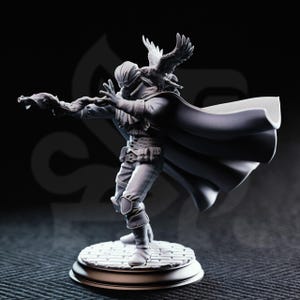 May include: A detailed, grayscale figurine of a person in a cloak, with an avian figure perched on their head. The figure is posed dynamically on a circular base with a cobblestone pattern. The person is wearing a hat, and the cloak is flowing.