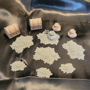 May include: Miniature fantasy game accessories, including two treasure chests, three coin purses, and several piles of small, textured, light gray objects, possibly representing coins or other treasure. The items are arranged on a dark, shiny surface.