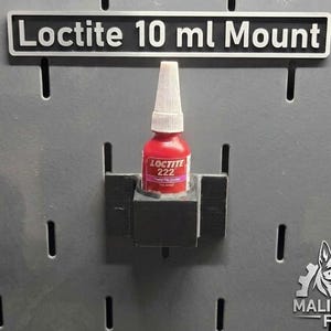 Puede incluir: Una botella roja de adhesivo Loctite 222 se sujeta en un soporte negro, montado en una placa perforada gris. El letrero sobre la botella dice "Loctite 10 ml Mount". El logotipo de Maligator Fab está en la esquina inferior derecha.