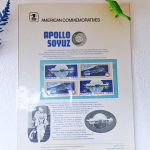 May include: A vintage postcard commemorating the Apollo-Soyuz Test Project, a joint space mission between the United States and the Soviet Union in 1975. The postcard features two stamps depicting the Apollo and Soyuz spacecraft docked together, with the text "Apollo Soyuz 1975" and "Apollo Soyuz Space Test Project".