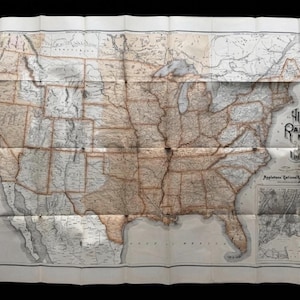 May include: A vintage folded paper map of the United States and Canada titled Appleton's Railway Map. The map features brown state and provincial borders, black text, and detailed railway lines printed on a cream-colored background with creases.