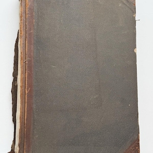 May include: An antique hardcover book with a dark gray fabric cover and brown leather corners. The spine is reinforced with brown leather, showing significant wear, fraying, and exposed binding along the left edge of the rectangular volume.