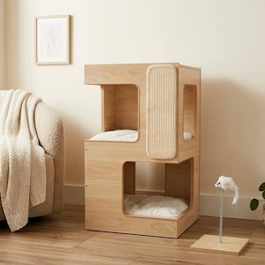 May include: A light wood cat tower featuring two levels with open square cutouts, white plush cushions inside each level, and a vertical textured scratching panel on the side. A separate small toy mouse on a spring base sits nearby.