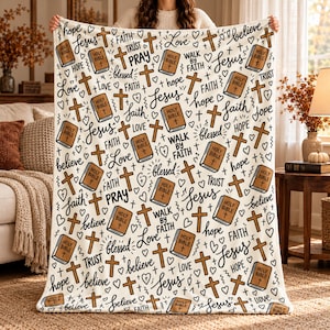 May include: A white fleece blanket featuring a repeating pattern of brown Holy Bible books, brown crosses, small hearts, and black cursive text including the words Jesus, faith, love, hope, believe, trust, pray, blessed, and walk by faith.